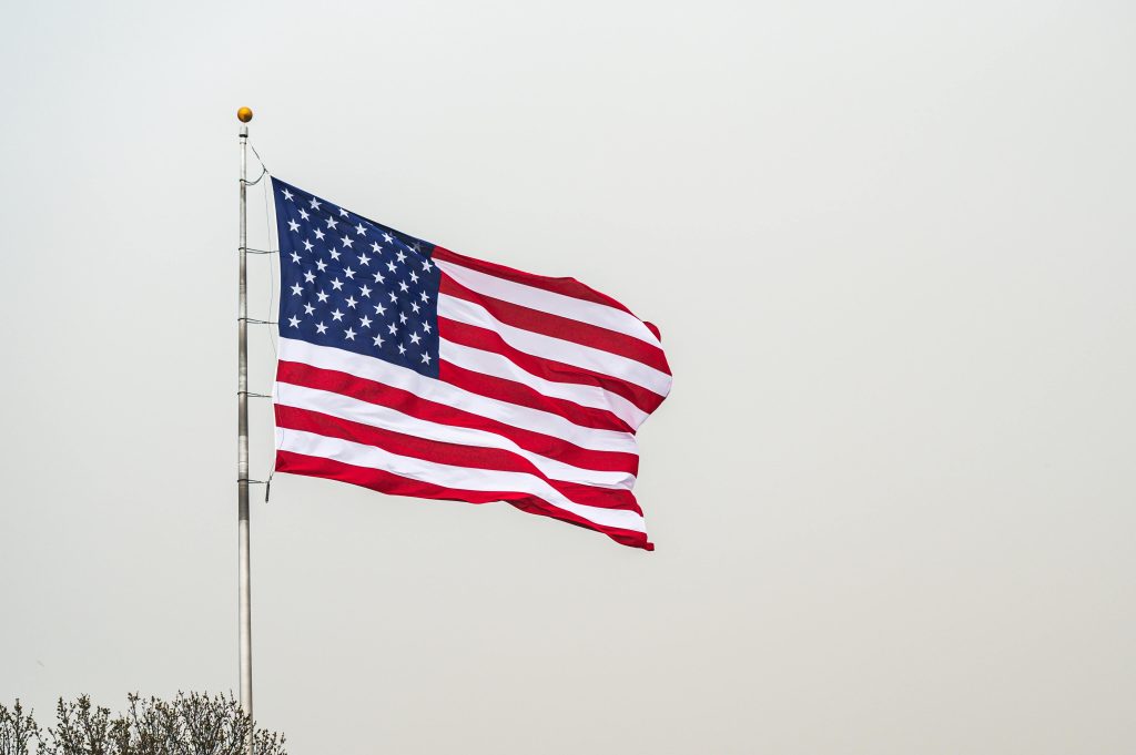 A striking image of the American flag waving on a flagpole set against a clear sky.